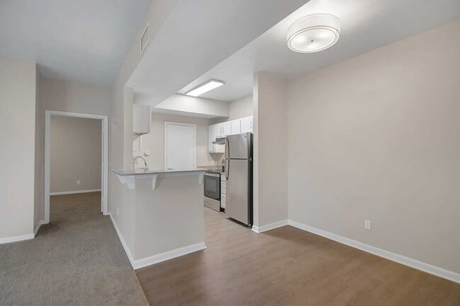 Dining and kitchen area with breakfast bar, white cabinetry, stainless steel appliances, and wood style flooring throughout