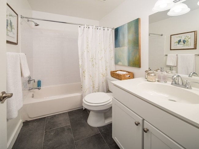 Bathroom with a single sink vanity, grey tile flooring, and a tub shower with subway tile