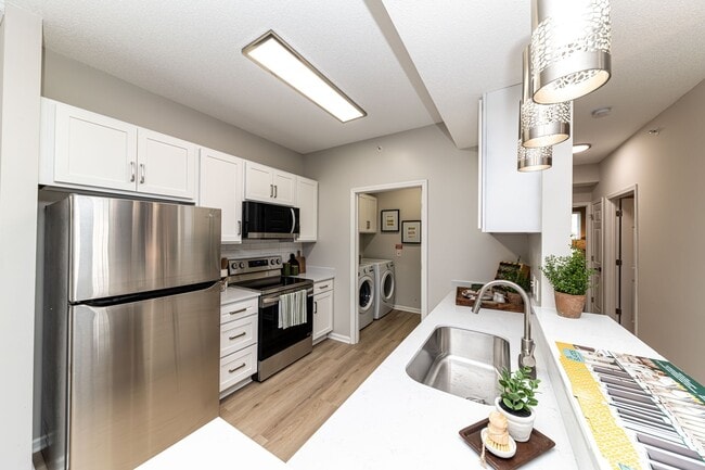 Kitchen with quartz counters, modern cabinetry, & stainless appliances - The Slates at Powdersville Apartments