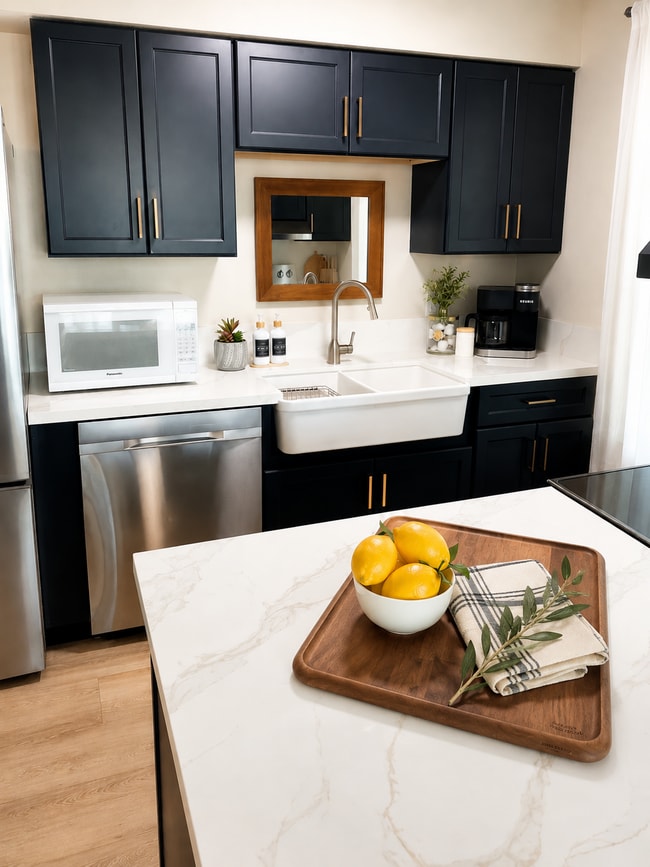 Kitchen with farmhouse sink, microwave, new cabinets, countertops, dishwasher, Keurig coffee maker.