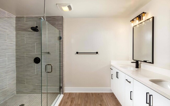 A tiled shower on one wall, sinks on the other, and room to move between.
