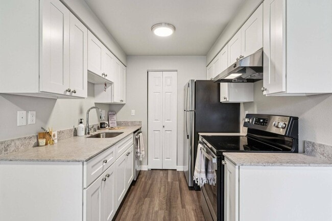 Bright, open-concept kitchen with stainless steel refrigerator and oven at Foster Creek Apartments, Tukwila.