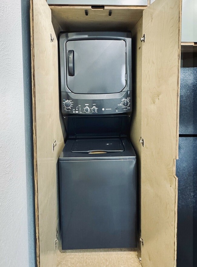Efficient stacked washer and dryer set in a sleek wooden closet, offering convenient in-home laundry solutions.