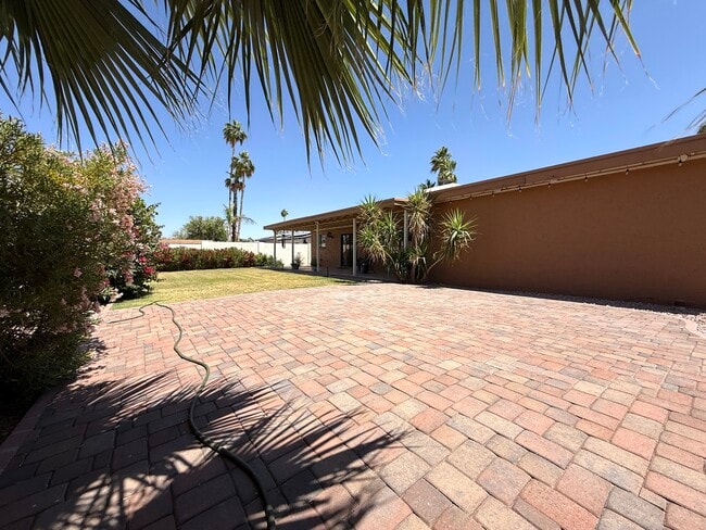Large, lush backyard includes large paver patio.