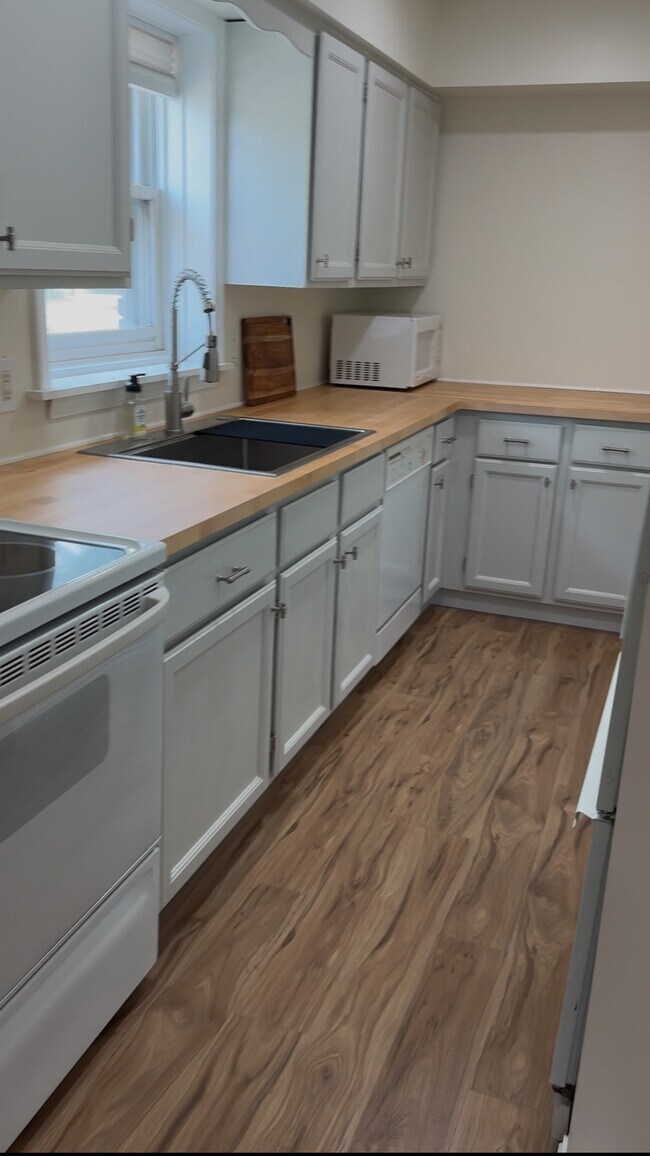Bright galley kitchen with butcher block counters, modern faucet, full appliances, and natural light - 328 N Allen St Unit 1