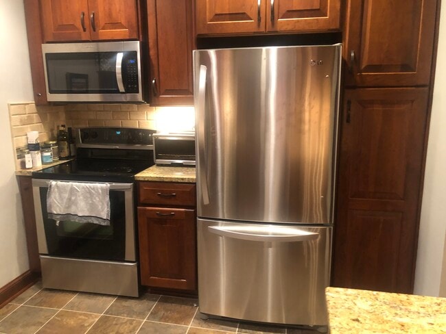 Cocina con refrigerador, estufa y microondas. Basura y despensa en el armario. - 4119 N Newhall St