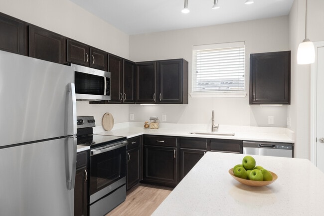 Kitchen with stainless steel appliances, quartz or granite countertop, espresso cabinetry, and hard surface vinyl plank flooring
