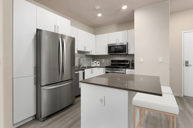 Renovated Package I kitchen with quartz countertops, white cabinetry, stainless steel appliances, hard surface vinyl plank flooring, and tile backsplash
