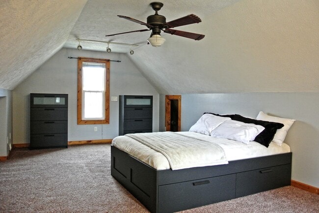 Spacious upstairs bedroom with wardrobe, ceiling fan, and two sets of track lighting.