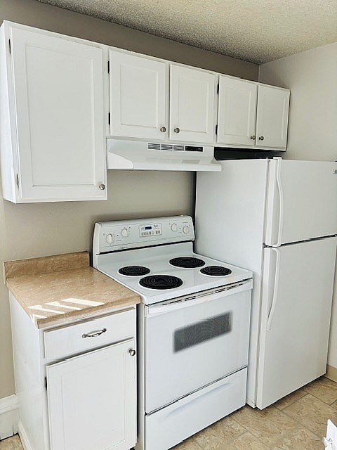 Cocina luminosa y compacta con gabinetes blancos, estufa eléctrica y refrigerador, perfecta para la vida moderna.