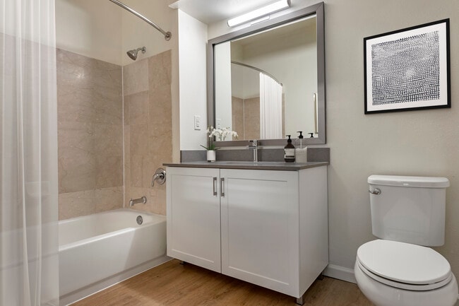 Renovated Package III bath with grey quartz countertops, white cabinetry, and hard surface plank flooring