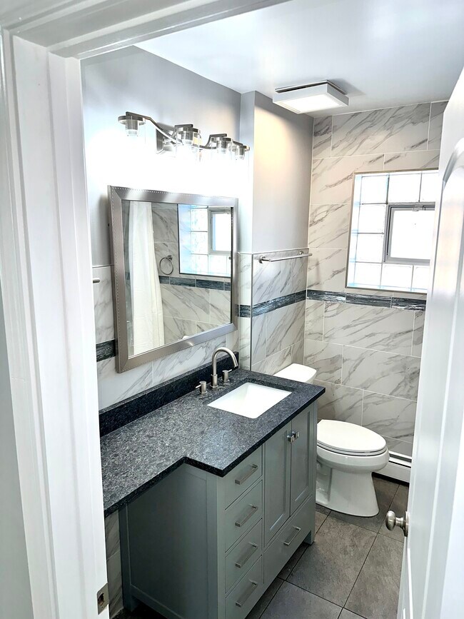 Baño completo recién reformado con una nueva encimera grande, inodoro Kohler y paredes y suelo alicatados. - 771 56th St Unidad 1st Floor