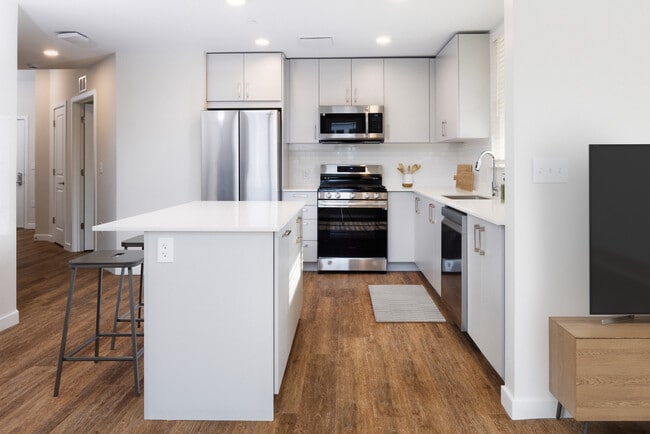 Kitchen with stainless steel appliances, white quartz countertop, light grey cabinetry, and hard surface flooring