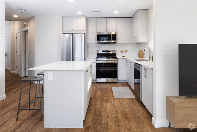 Finish Scheme II kitchen with stainless steel appliances, white quartz countertop, light grey cabinetry, and hard surface flooring (representative photo) - Avalon Governors Park Rental