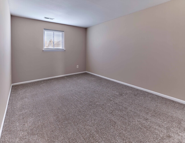 Spacious bedroom with carpet flooring at Village Square Apartments.