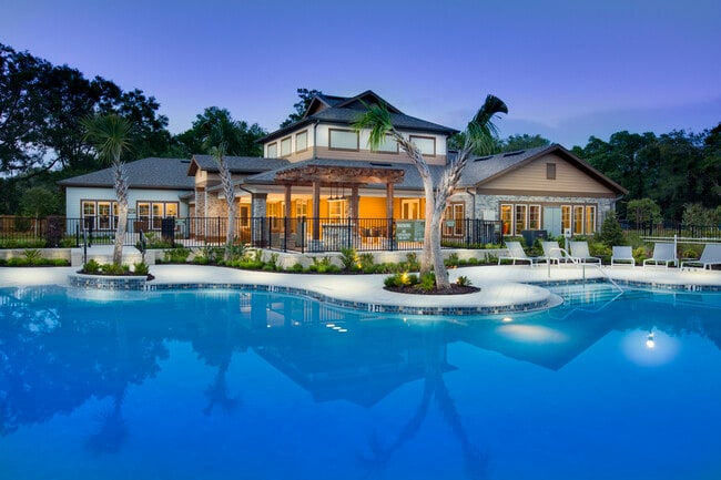 Photo overlooking swimming pool with outdoor seating, with the clubhouse in the backrgound. - Brookview at Citrus Park Apartments