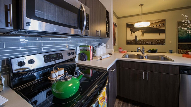 Apartment Kitchen with Stainless Steel Appliances, quartz counters and wood floors. - Griffis Lakeline Station Apartments