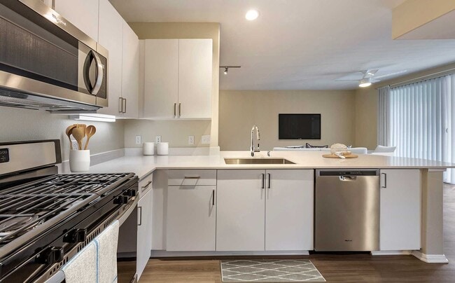 Renovated Package I kitchens with light grey quartz countertops, new white cabinetry, stainless steel appliances, upgraded fixtures, and hard surface flooring throughout