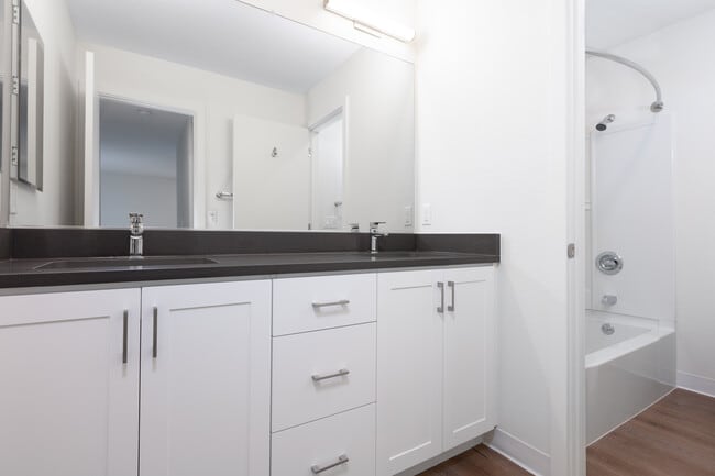 Bathroom with double vanity, grey countertop, white cabinetry and hard surface flooring