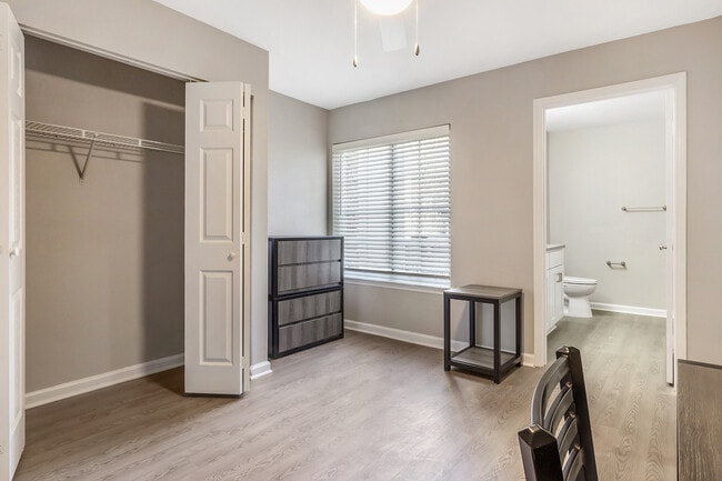 Experience modern elegance in this sunlit bedroom with an en-suite bathroom and ample storage. - Village Green Student Housing