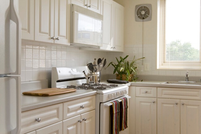 Cocina con armarios blancos, encimeras blancas, electrodomésticos blancos y salpicadero de azulejos