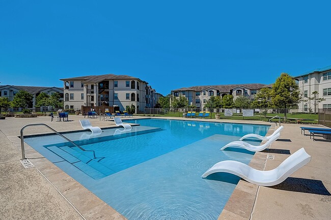 Pool with lounging chairs in water. - Capri Villas at the Lake Apartments