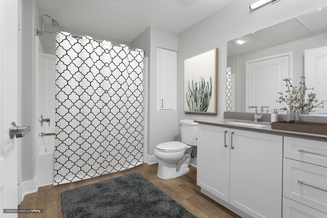 Renovated Package I bath with white cabinetry, grey quartz countertop, and hard surface flooring