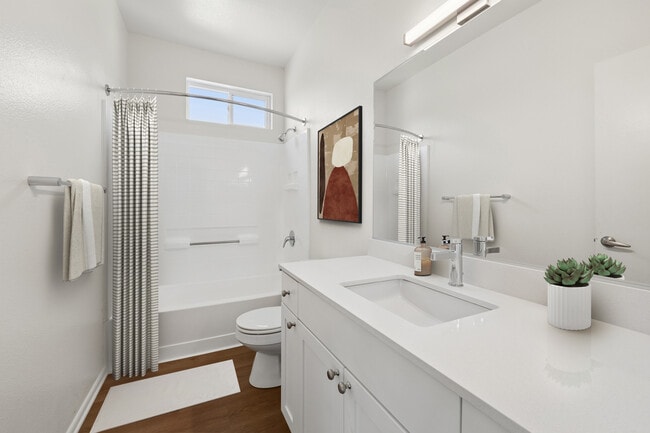 Renovated Package I bath with white quartz countertop, white cabinetry, and hard surface flooring