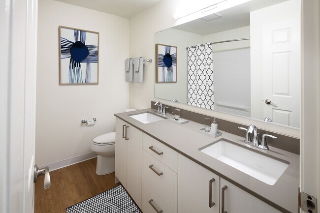 Renovated Package I bath with grey quartz countertop, white cabinetry, and hard surface flooring