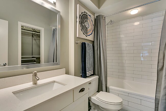 Beautiful modern white bathroom with white subway tiles, soaking tub, and framed mirror with white quartz countertop