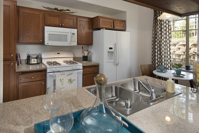 Classic Package I kitchen with maple cabinetry, beige speckled granite countertops, white appliances, and tile flooring