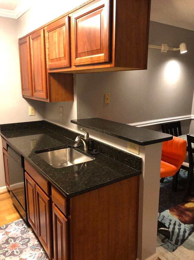 Kitchen with granite countertops, stainless sink, and breakfast bar