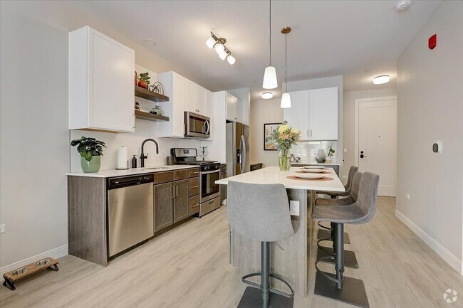 Kitchen with island, stainless steel whirlpool appliances, quartz countertops, floating shelves and two tone cabinets - Lilac Station Rental