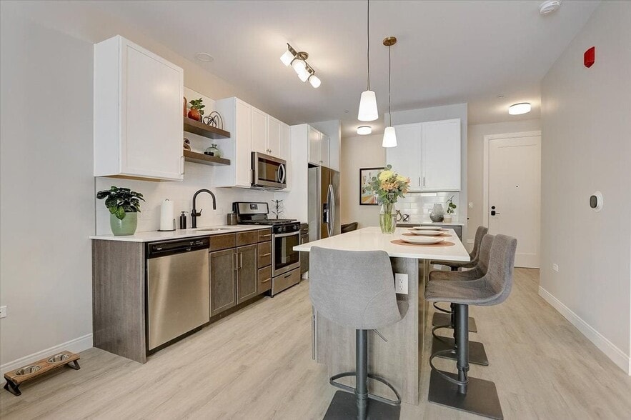 Kitchen with island, stainless steel whirlpool appliances, quartz countertops, floating shelves and two tone cabinets