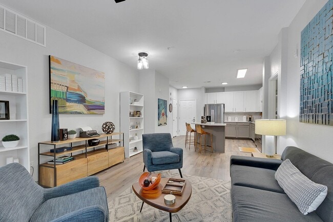 Modern open-concept living room with stylish decor, cozy seating, and a sleek kitchen area, perfect for entertaining.