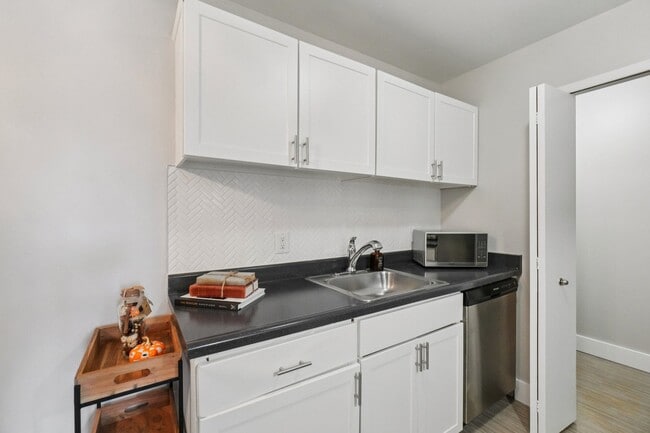 Enjoy stylish kitchens with bright white cabinetry and sleek dark countertops, professionally operated by Highlands Vista Group. - Bainbridge Park