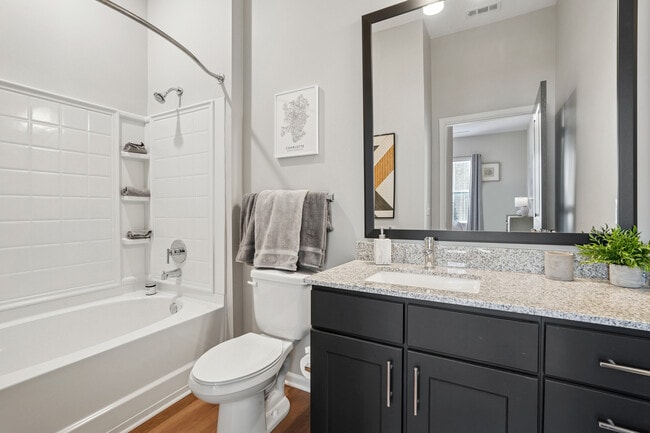 Bath with dark cabinetry, speckled granite countertops, and hard surface flooring