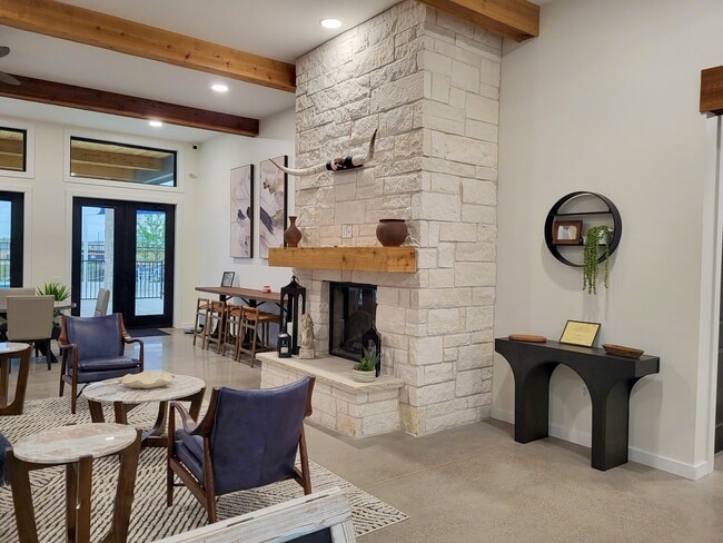 Cozy seating and dining areas beside a tall stone fireplace, with modern decor and natural light from tall windows