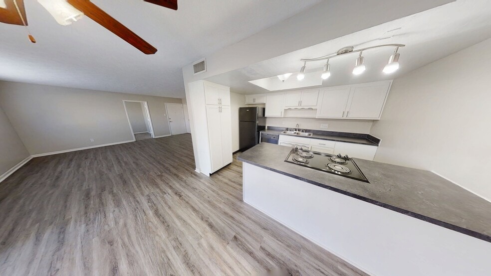 Open-plan kitchen and living area with sleek countertops, modern lighting, and elegant wood flooring.