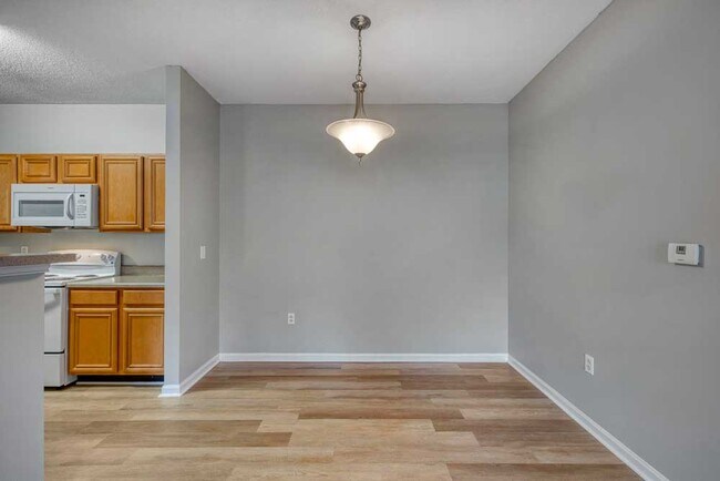 Dining nook with gray walls, wood style flooring, hanging light fixture, and open flow into the kitchen area