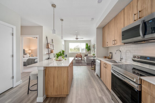 Kitchen with oak cabinetry, stainless-steel appliances, pendant lighting, hard-surface flooring and granite countertops