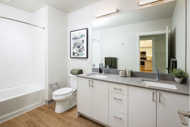 Bath with grey quartz countertops, white cabinetry, and hard surface flooring