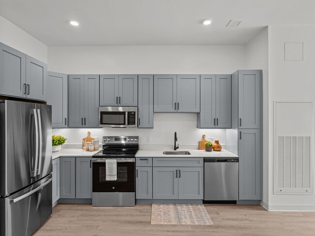 Modern kitchens with quartz countertops and stainless steel appliances at The Elmwood Apartments.