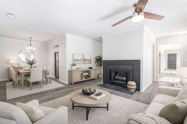 Bright open-concept living room at Sugar Creek Apartments in Winston-Salem, NC featuring a cozy fireplace, modern finishes, and connected dining space. - Sugar Creek Apartments