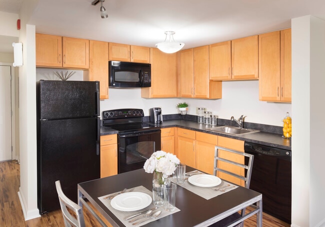 Dining area and kitchen with black appliances, black countertops and hard surface flooring