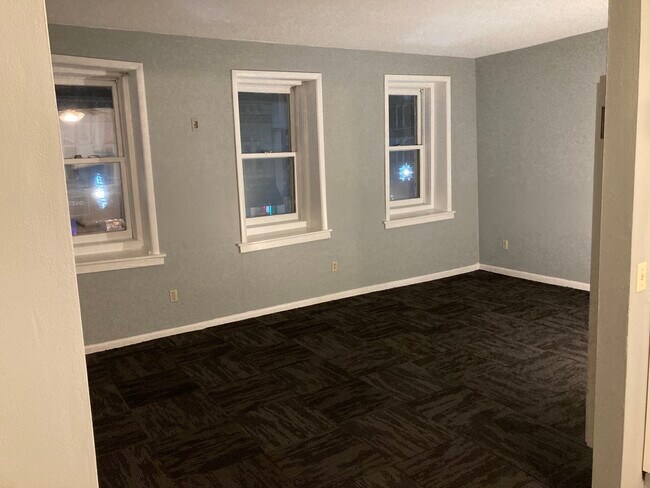 Newly painted and carpeted living room. Large Windows with high ceilings. Overlooks 2nd Street. - 116 2nd St E