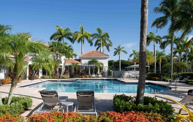 The heated pool at Polo Lakes is framed by palms, flowers, and lounge seating.