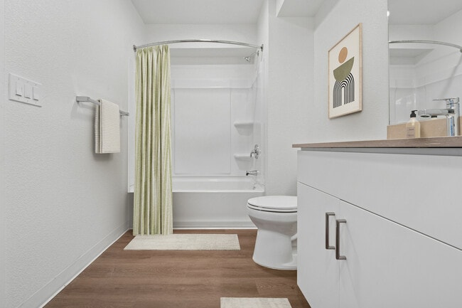 Renovated Package bath with beige quartz countertops, white cabinetry, and hard surface flooring