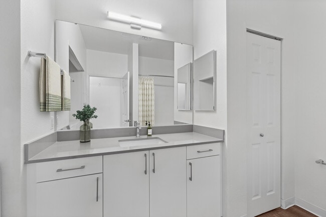 Paquete I renovado: baño con gabinetes blancos, encimeras de cuarzo gris y pisos de superficie dura.