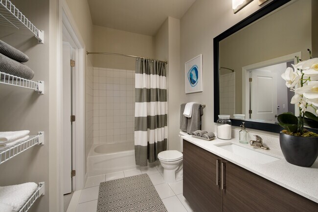 Bathroom with storage space, tile floor, European-style cabinetry, white countertop, shower with tile backsplash and hard surface flooring